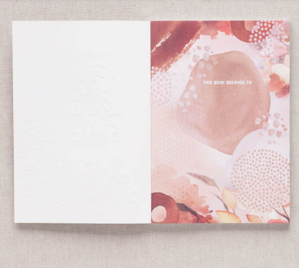 Book opened to the This Book Belongs To page with a pink watercolor design
